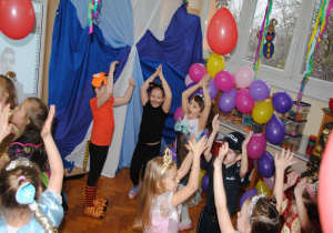 dzieci śpiewają i tańczą z rękami uniesionymi do góry